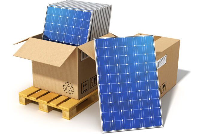 Creative solar power generation technology, alternative energy and environment protection ecology business concept: group of stacked solar battery panels packed in cardboard box on shipping pallet ready for installing and mounting isolated on white background
